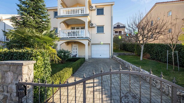 A two-story residential building with a balcony, a garage, and a paved driveway. - Holiday apartment with balcony (Njivice)