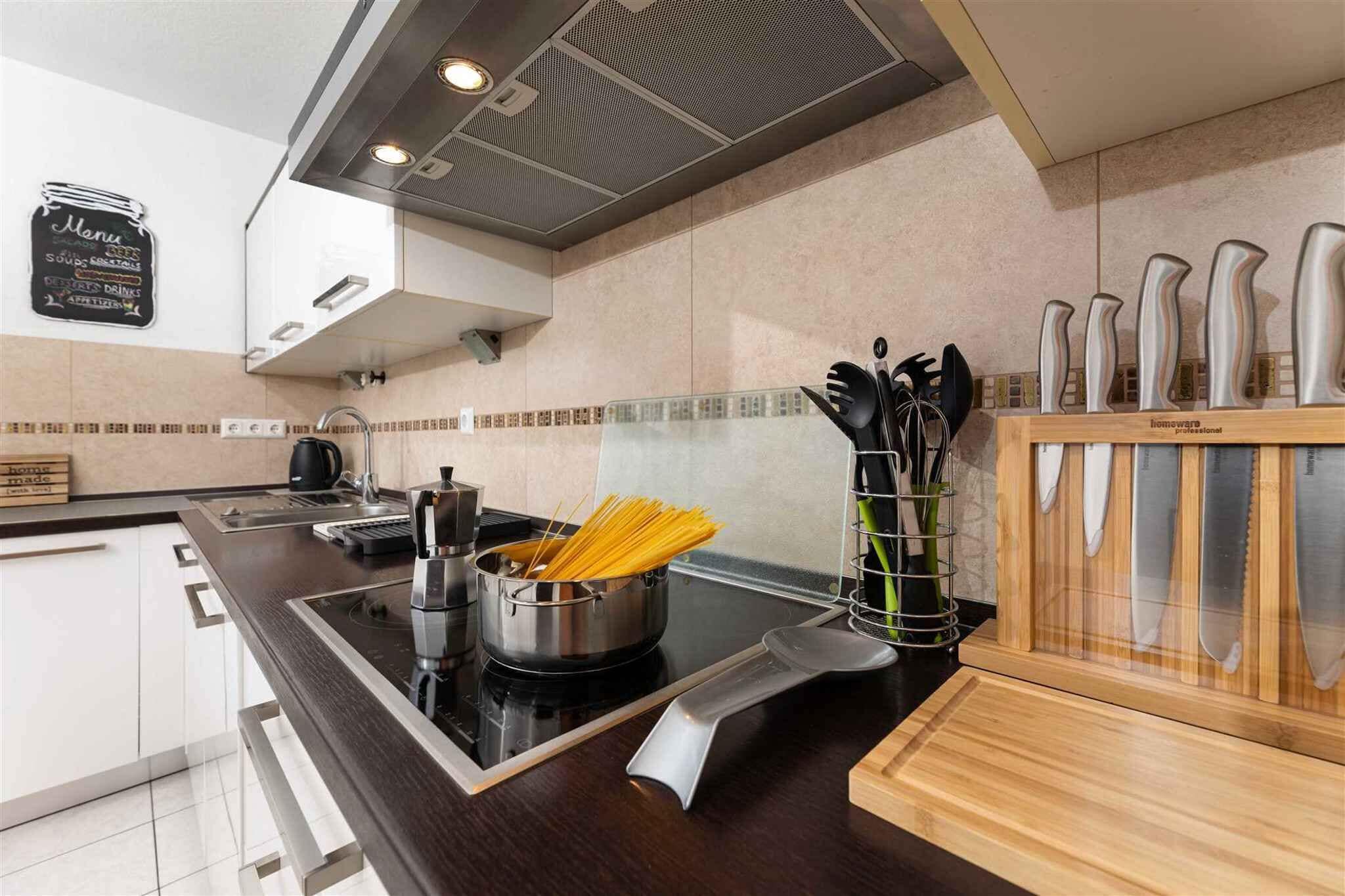 Una cucina moderna con un piano di lavoro nero, elettrodomestici in acciaio inossidabile e un portauova di legno.