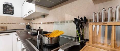 A modern kitchen with a black countertop, stainless steel appliances, and a wooden utensil holder.