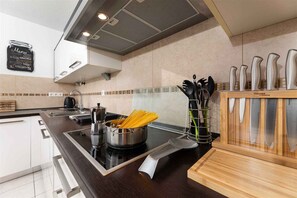 A modern kitchen with a black countertop, stainless steel appliances, and a wooden utensil holder.