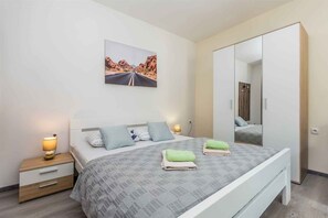 A bedroom with a bed, bedside tables, a mirror, and a painting on the wall.