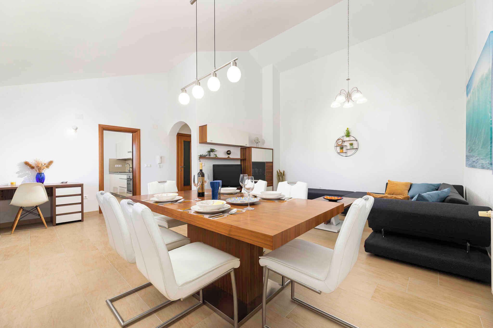 Un espace repas moderne avec une table en bois, des chaises blanches et des luminaires suspendus.