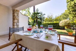 Mesa al aire libre con pared de piedra, planta en maceta y vista a la vegetación.