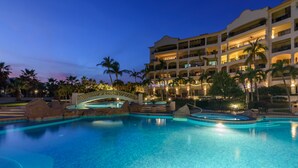 Un hotel con una piscina grande, palmeras y un puente.