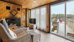 A cozy living room with wicker furniture, a flat-screen TV, and a fireplace.