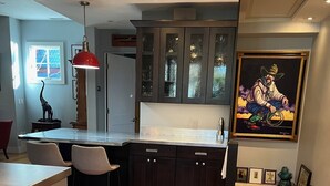 A modern kitchen with dark cabinets, a marble countertop, and a rustic wooden table. - The Perfect In Town Home Away from Home (Durango)