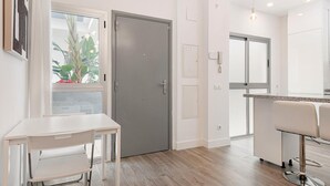 A modern kitchen with a grey door, a white table with chairs, and a bar area with a mirror.