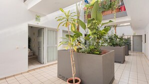 A modern apartment with a spacious balcony, large grey planters, and a view of the cityscape.