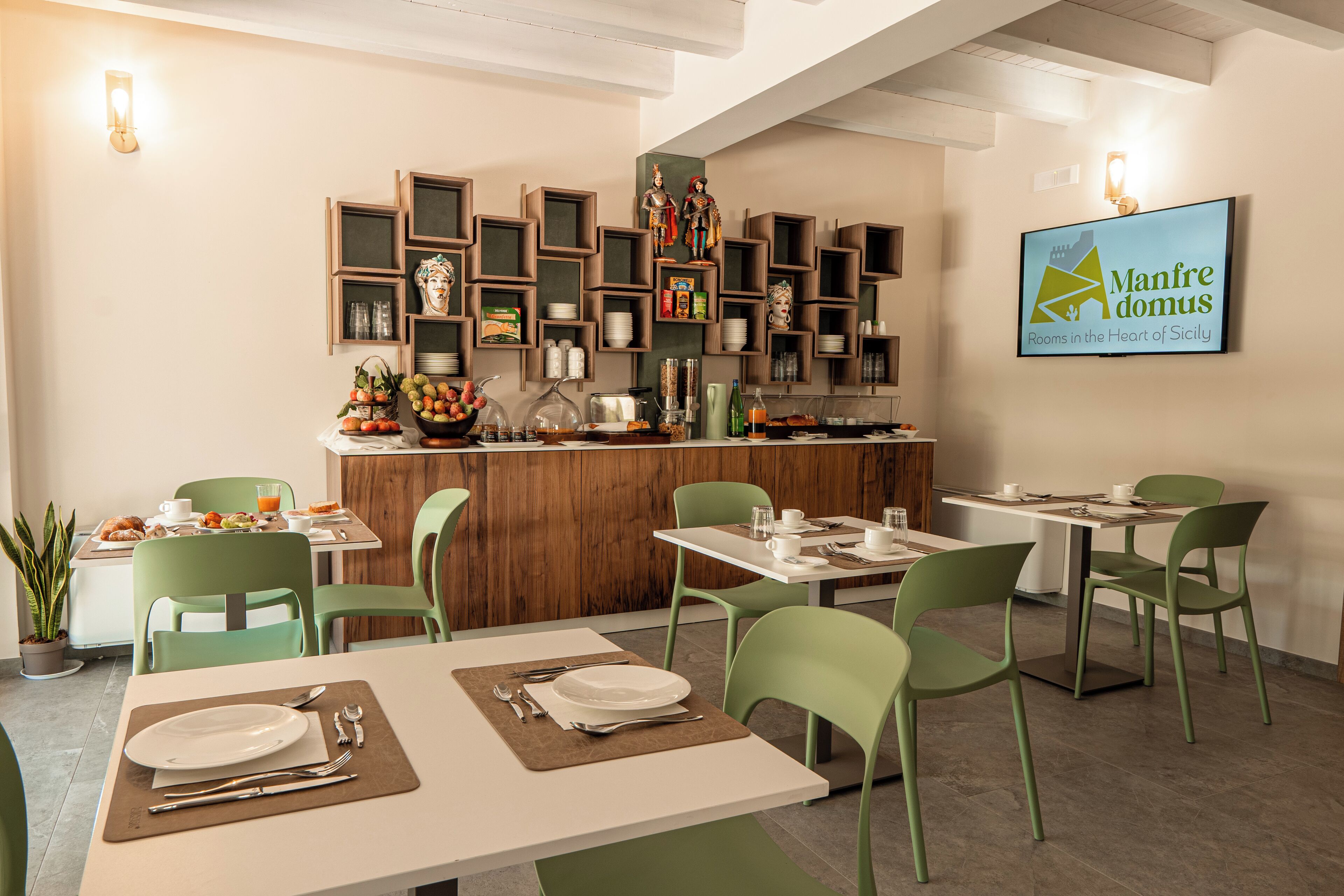 Un ristorante con sedie e tavoli verdi, un'area bar con scaffali e un cartello fissato al muro.