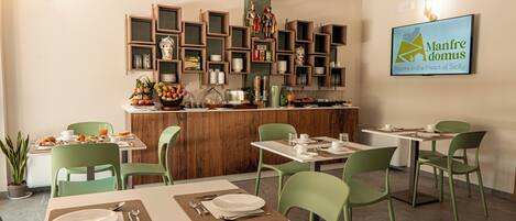 Un ristorante con sedie e tavoli verdi, un'area bar con scaffali e un cartello fissato al muro.