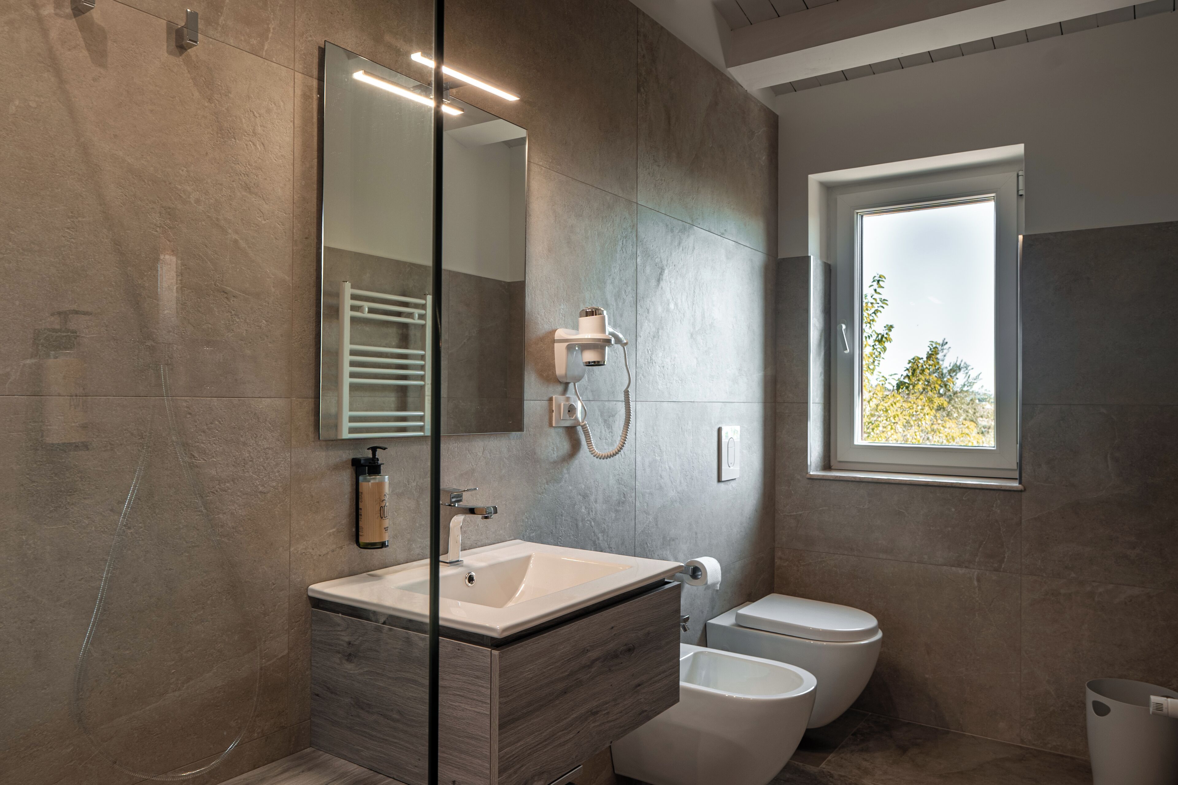 A modern bathroom with a large mirror, a sink, a toilet, and a shower.