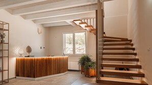 Et moderne receptionområde med en træreception, en trappe med trætrapper og et stort vindue der giver naturligt lys.