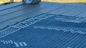 Une statue de Bouddha sur une plateforme en bois, sur laquelle est posé un tapis à motifs bleus.