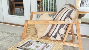 Una sedia di legno con schienale intrecciato e cuscini, posizionata su un tappeto decorato.