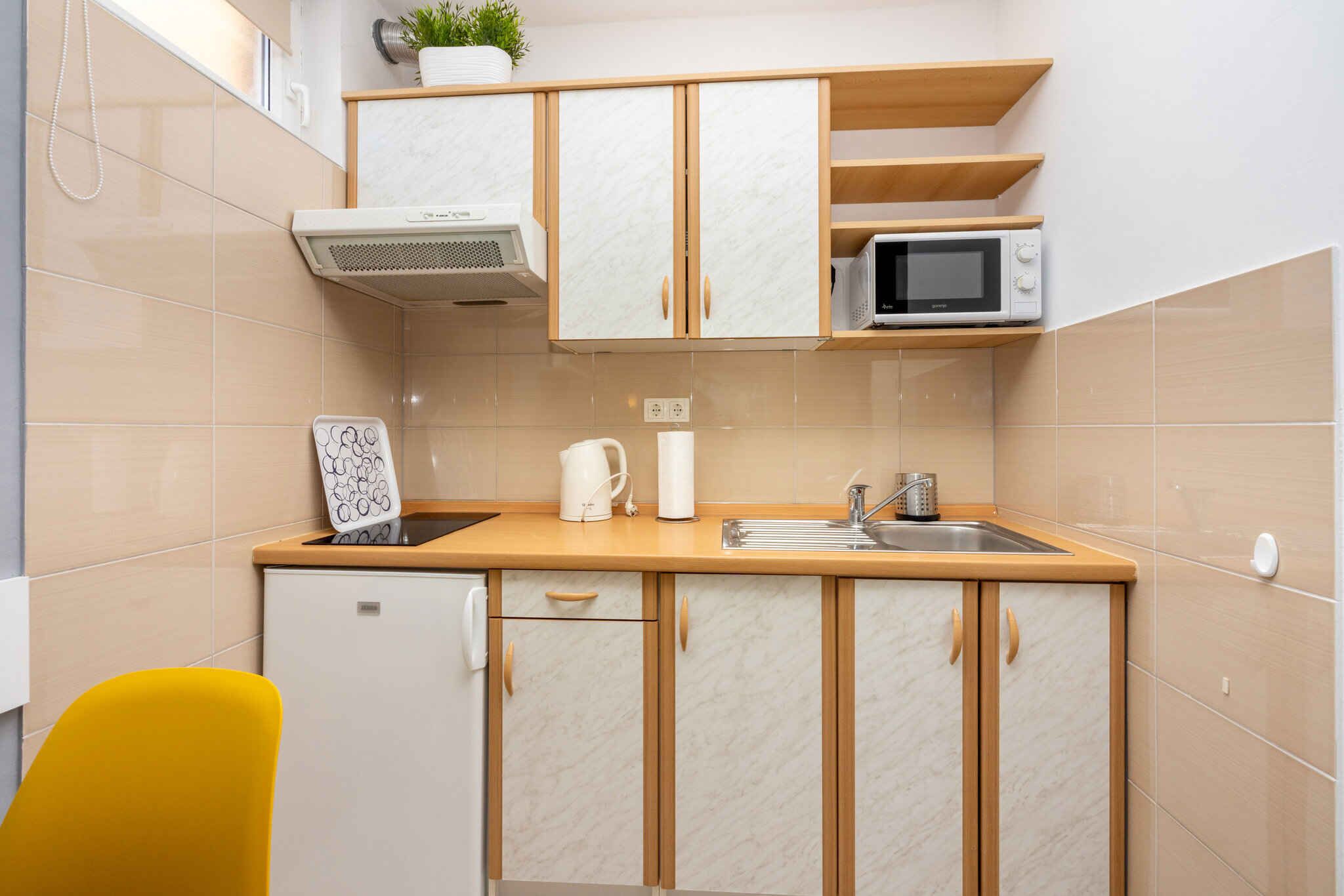 Eine kleine Küche mit einer Mikrowelle, Spüle und einem Kühlschrank.