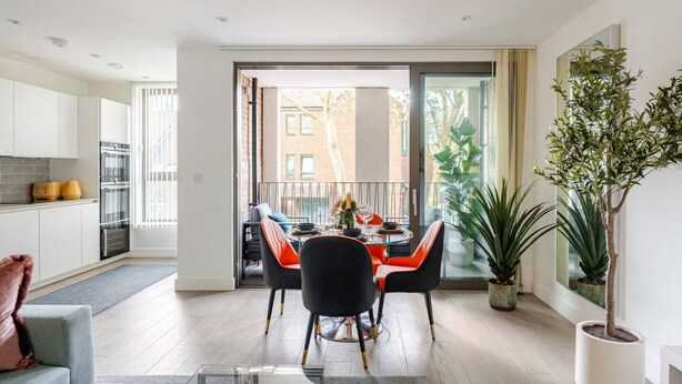 Eine moderne Wohnung mit Essbereich, Küche und einem Balkon mit Blick auf Gebäude.