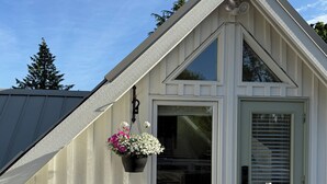 A white building with a gabled roof, a window, and a door with a cross-shaped design.