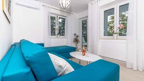 Un salon moderne avec un canapé de couleur turquoise, une petite table blanche et une plante en pot.
