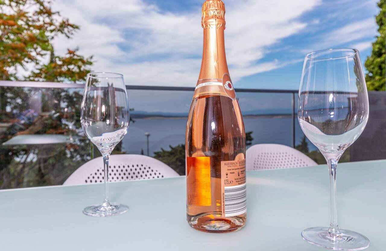 Une bouteille de champagne et deux verres sur une table, avec vue sur l’océan.