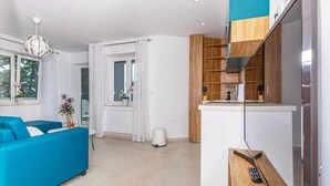 Un salon moderne avec un canapé bleu, un coin cuisine doté de meubles en bois et une table à manger.