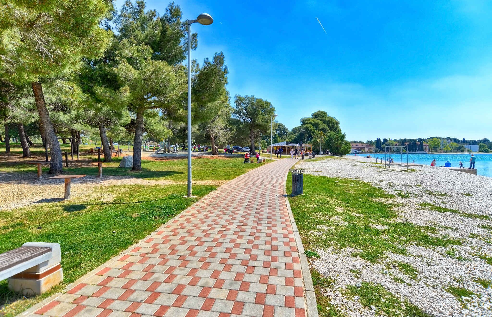 A paved walkway leading to a beach with a clear view of the water.