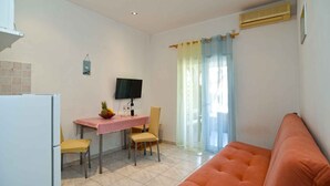 A compact kitchen with a dining table, chairs, a TV, and a sofa.