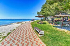 Une promenade pavée longeant une plage, agrémentée de bancs et de kiosques.