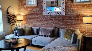 Una sala de estar con pared de ladrillo, un sofá modular, una mesa de centro y dos lámparas.