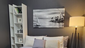 Un dormitorio con cama, una estantería, un cuadro y una lámpara de pie.