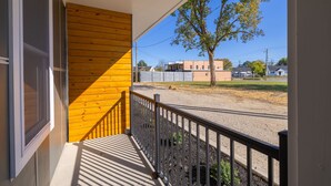 A porch with a wooden railing and a view of a street with buildings and a tree. - Tourist Home of Richmond 1-bedroom apartment - Church Hill North TH06 (Richmond)