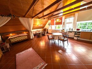 Une chambre confortable située sous les toits, avec un lit, un petit canapé et une table à manger avec des chaises.