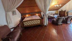 Ein Schlafzimmer mit Holzboden, einem Bett mit Kopfteil, zwei Stühlen, einem Tisch und einer Lampe.