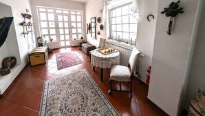 A spacious living room with a large window, a chessboard, a patterned rug, and a cozy chair. - Holiday apartment with wifi and air conditioning (Kehidakustány)