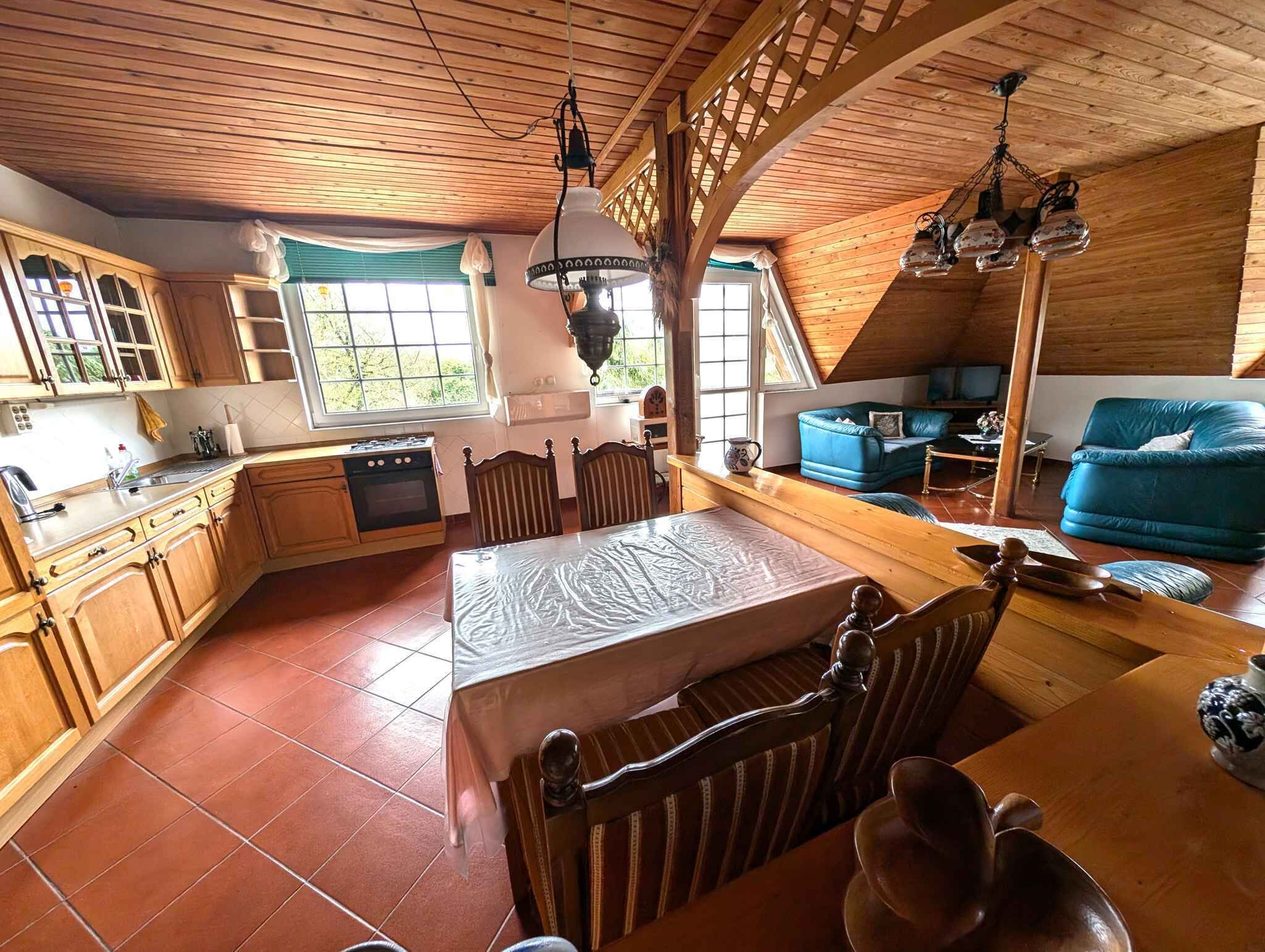Une cuisine chaleureuse avec des meubles en bois, une table à manger et un canapé bleu dans un chalet à l’allure rustique.
