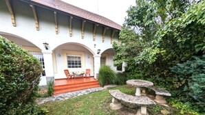 A building with a covered patio, stone steps, and two outdoor tables. - Holiday apartment with terrace and garden (Kehidakustány)