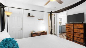 A bedroom with a bed, bedside lamp, dresser, and a television.