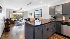 A modern kitchen with a central island, built-in appliances, and a dining area with a view.