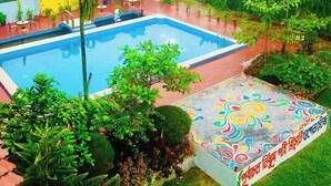 Une piscine entourée d’un jardin et agrémentée d’une fresque murale aux couleurs vives.