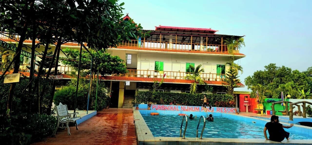 A hotel with a swimming pool, a multi-story building, and lush greenery.