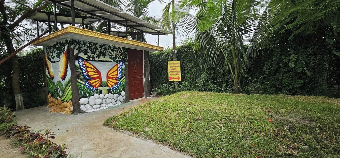Una pequeña estructura colorida con un mural de mariposas, una puerta roja y un letrero en un entorno tropical.