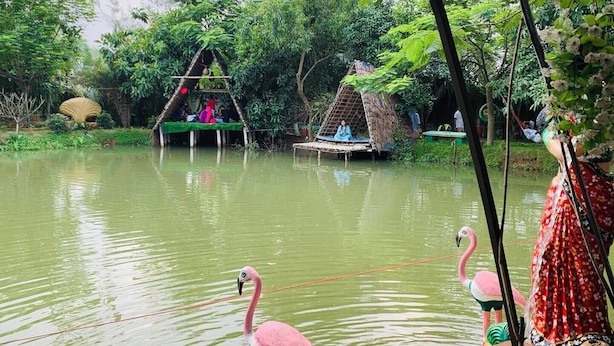 Une rivière avec un bateau en bois, un flamant rose et une petite cabane avec un toit de chaume.