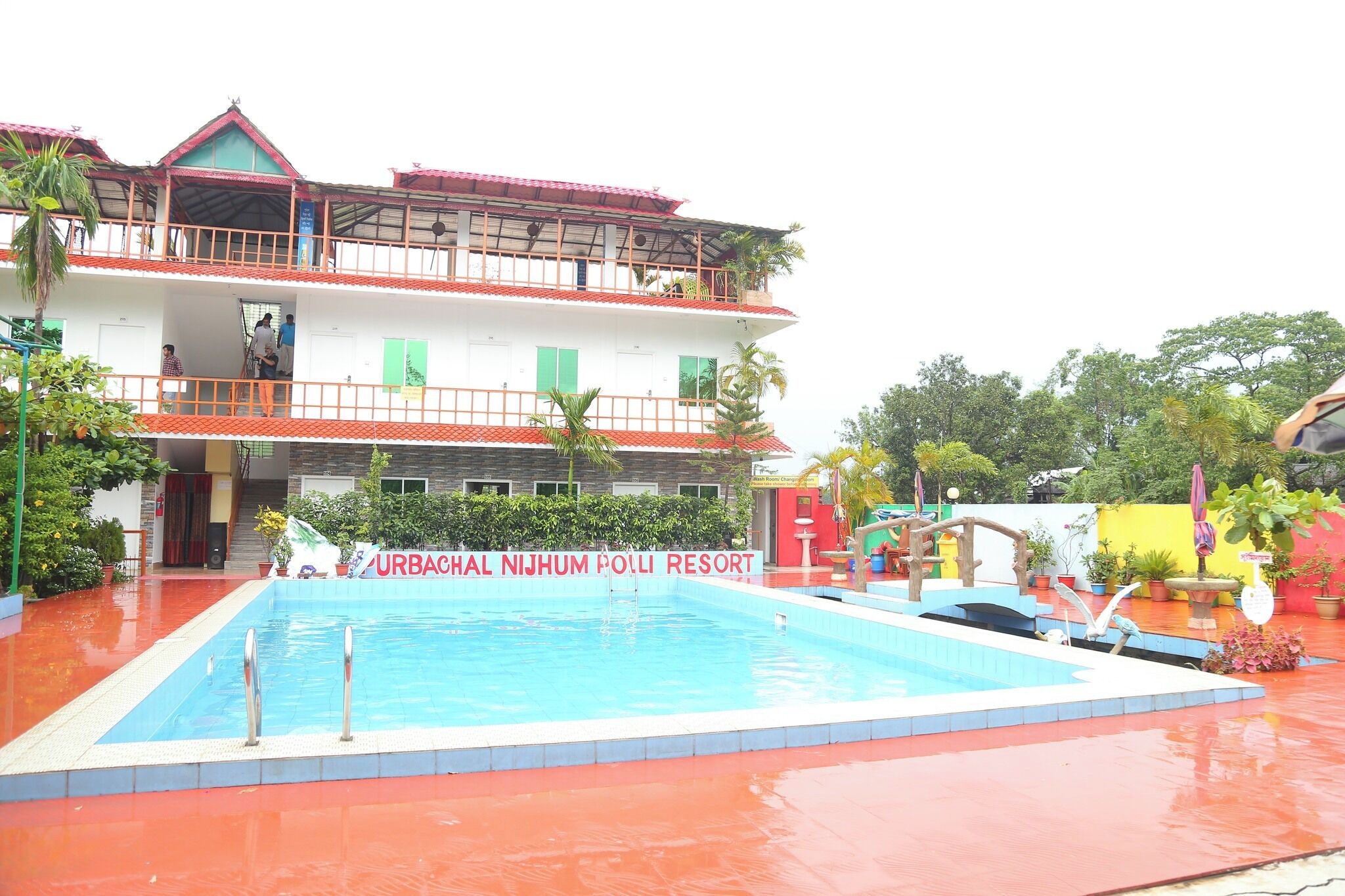 A resort with a swimming pool, a multi-story building, and a red roof.