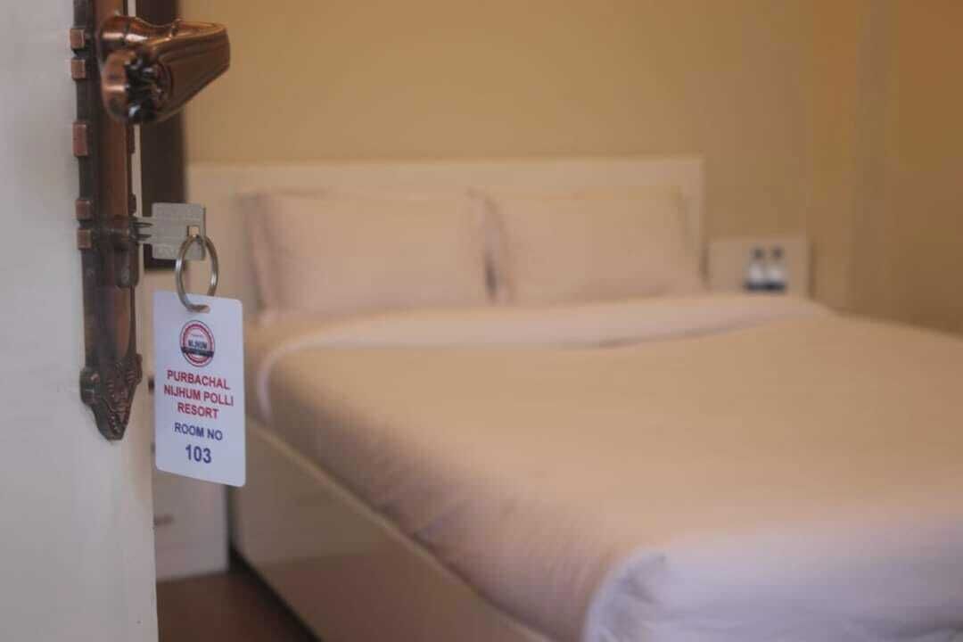 A hotel room with a bed, a door with a keycard lock, and a sign indicating room number 103.