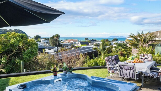 A hot tub with a view of the ocean and houses in the background.