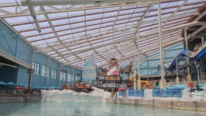Parque acuático interior con una piscina grande, toboganes y diversas atracciones acuáticas.