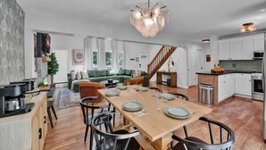 Una cocina amplia con comedor, piso de madera y una lámpara moderna.