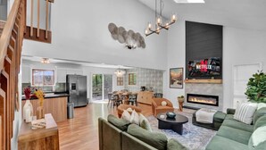 Un salón amplio con un sofá verde, una chimenea y una cocina al fondo.