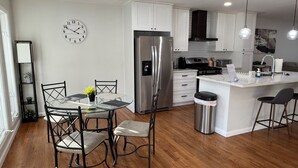 Una cocina moderna con armarios blancos, electrodomésticos de acero inoxidable y una isla central con taburetes de bar.