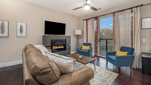 Ein Wohnzimmer mit Kamin, einer Couch, zwei Sesseln, einem Couchtisch und einem Deckenventilator.