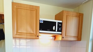 A compact kitchen with wooden cabinets, a microwave, a dishwasher, and a sink.
